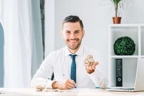 Courtier immobilier tenant une petite maison en bois