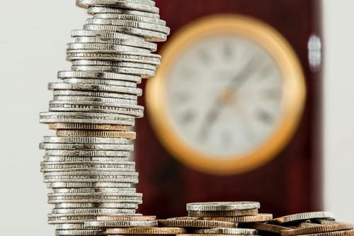 Pile de pièces de monnaie devant une horloge