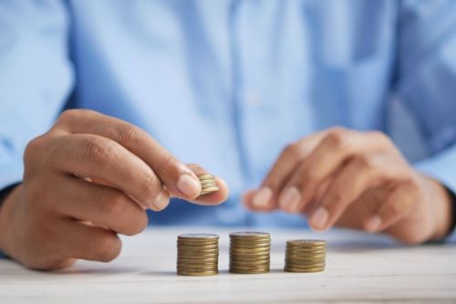 Homme déposant des pièces sur des piles d'argent