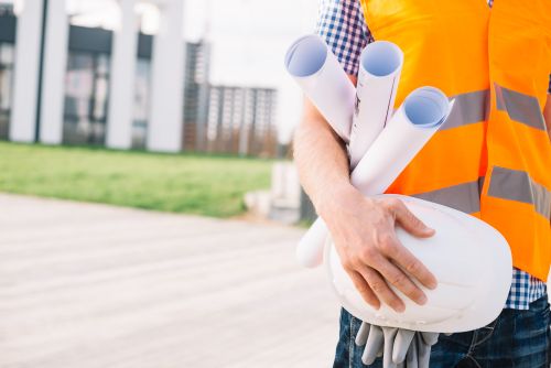 Arpenteur-géomètre tenant des plans et un casque