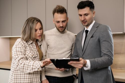 Couple d’acheteurs regardant le contrat de courtage avec un agent immobilier 