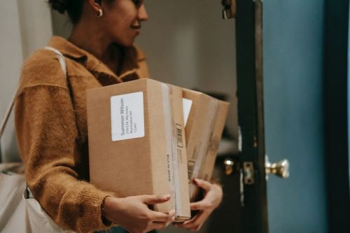 Femme entrant dans son nouveau logis avec deux colis dans les mains