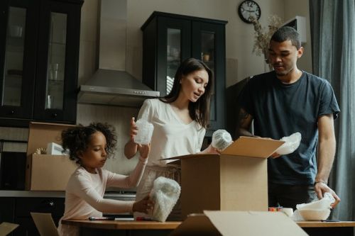 Famille emballant des articles de cuisine dans une boite de déménagement
