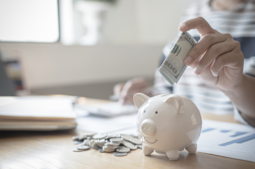 Personne économisant en mettant de l'argent dans une tirelire