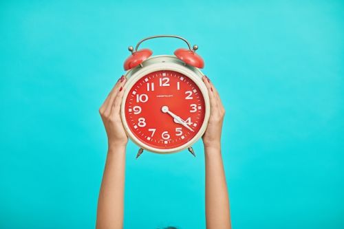 Personne tenant une horloge pour indiquer le temps qui passe