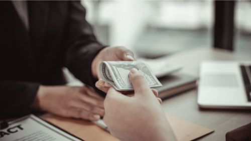 Client donnant une liasse d'argent à son prêteur hypothécaire