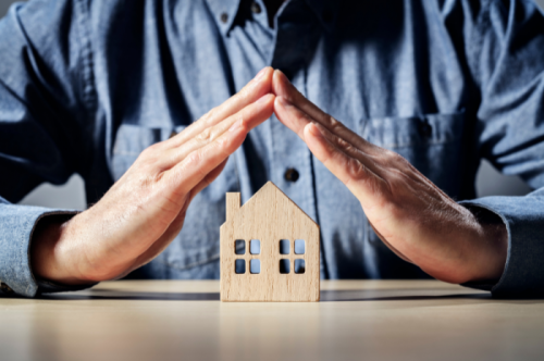 Petite maison en bois protéger par des mains