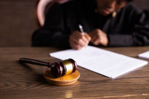 Maillet devant une juge écrivant un rapport
