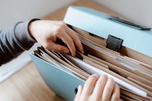 Personne cherchant un document dans un porte-documents en accordéon
