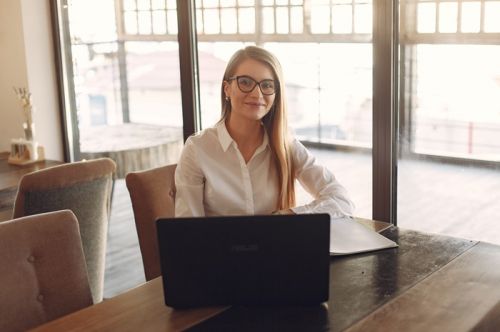 Courtière immobilière souriante assise derrière un ordinateur portable